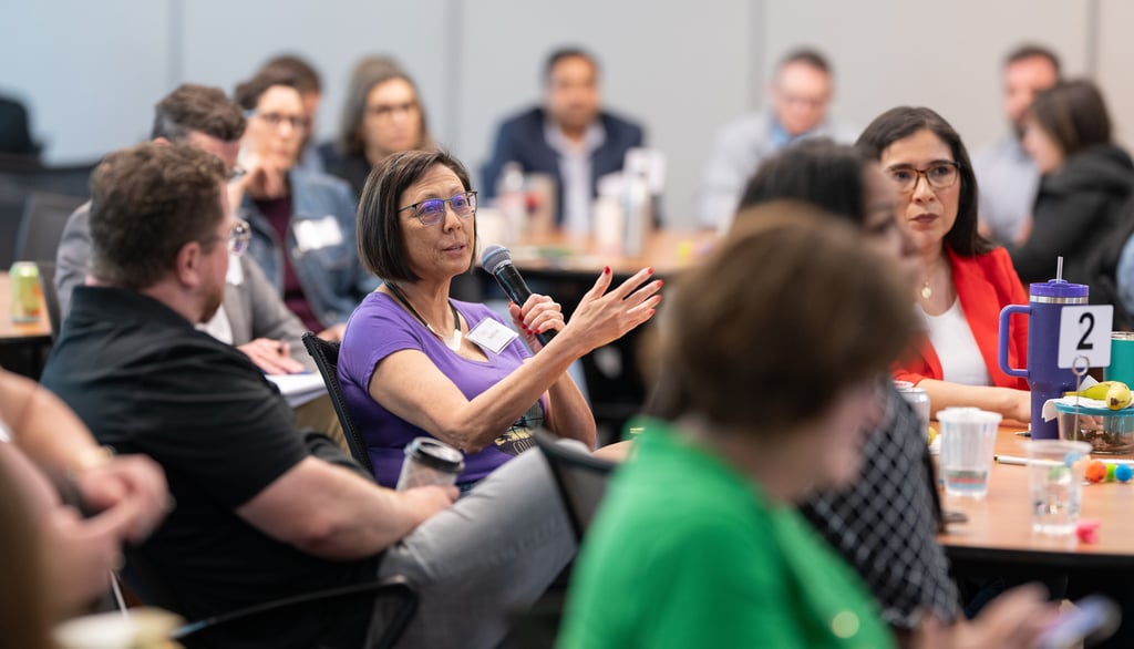 Leadership Austin participant speaks into a microphone during a thoughtful group discussion 