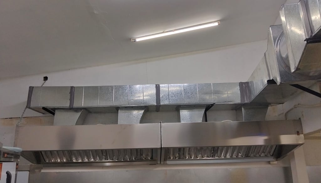 Industrial stainless steel commercial kitchen exhaust hood with silver ventilation ducting