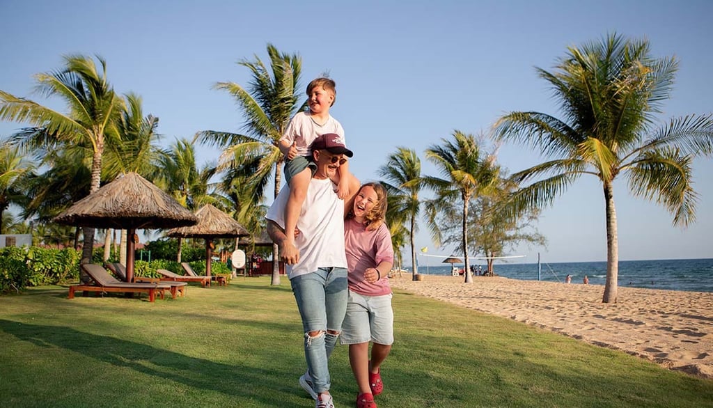 Family photoshoot at Mövenpick Resort Phu Quoc — father carrying son, walking along the lawn