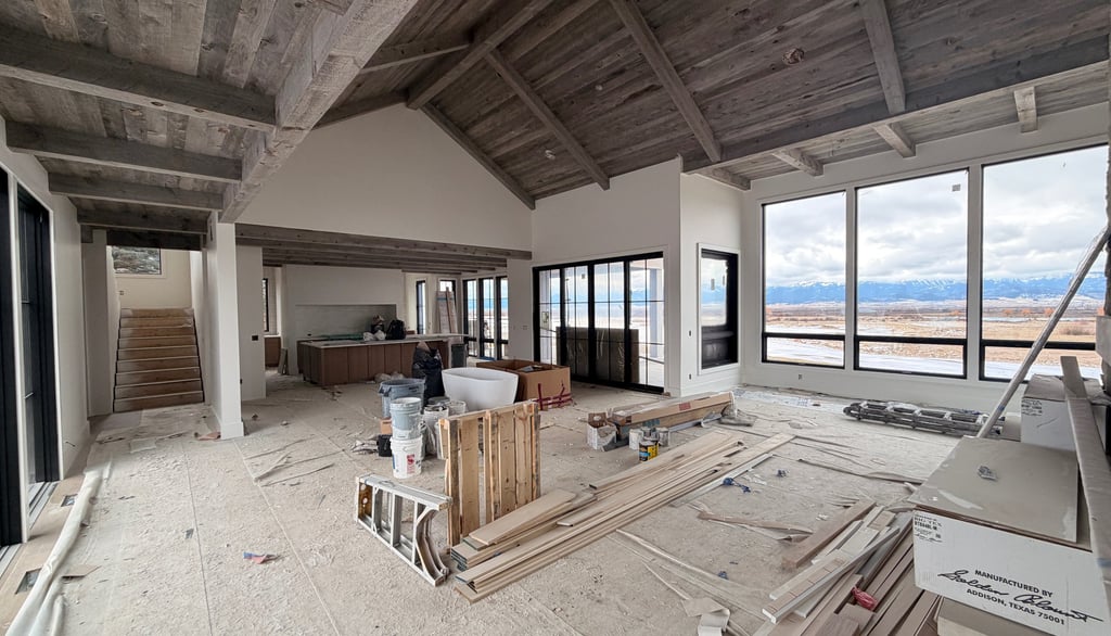 Custom home interior under construction with vaulted wood ceilings and large scenic windows.