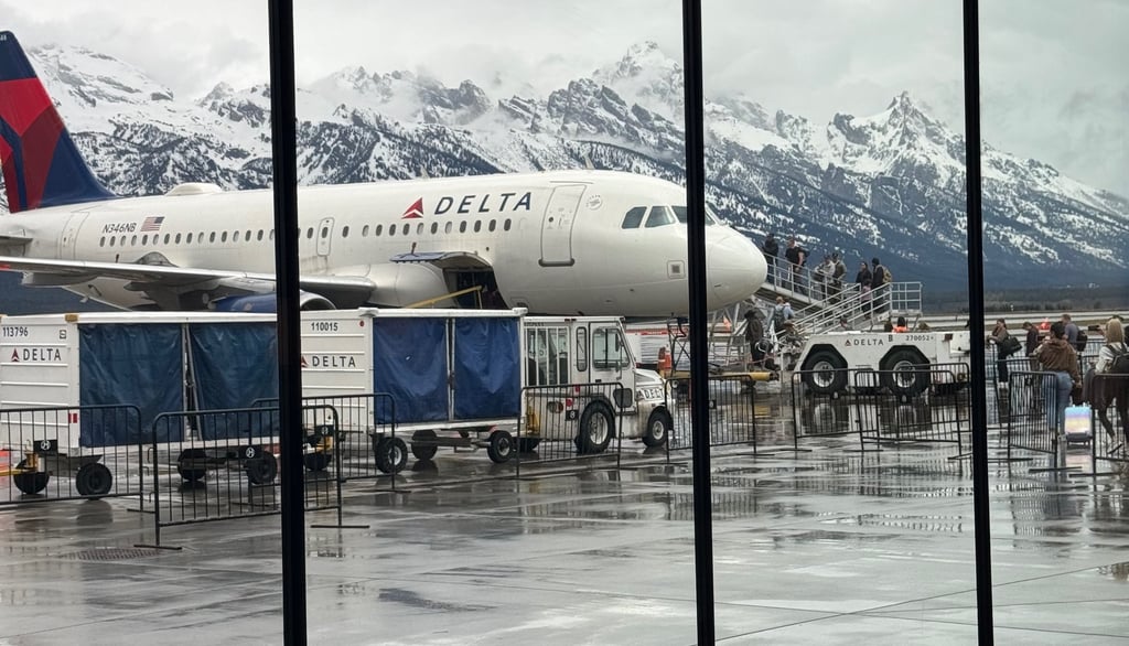 A Delta Airlines plane at the Jackson Hole, WY airport with the Tetons in the background.