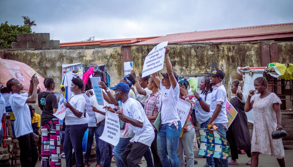 Image of Crowds holding placards with various wors promoting Sign Language.