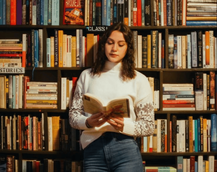 a woman standing in front of a bookcase with books on it