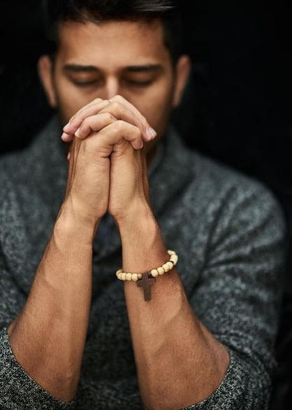 A young man praying with his eyes closed