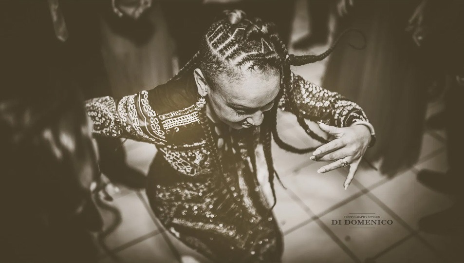 Invitée en robe brodée et tresses dansant vue d’en haut, ambiance mariage festive sépia.