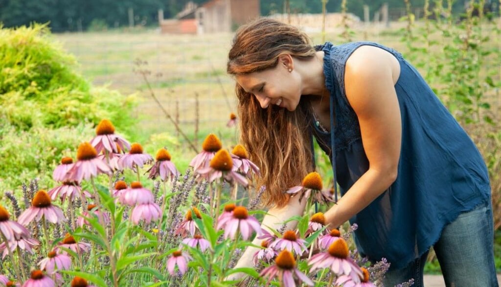 a woman in a blue shirt is looking at a flower