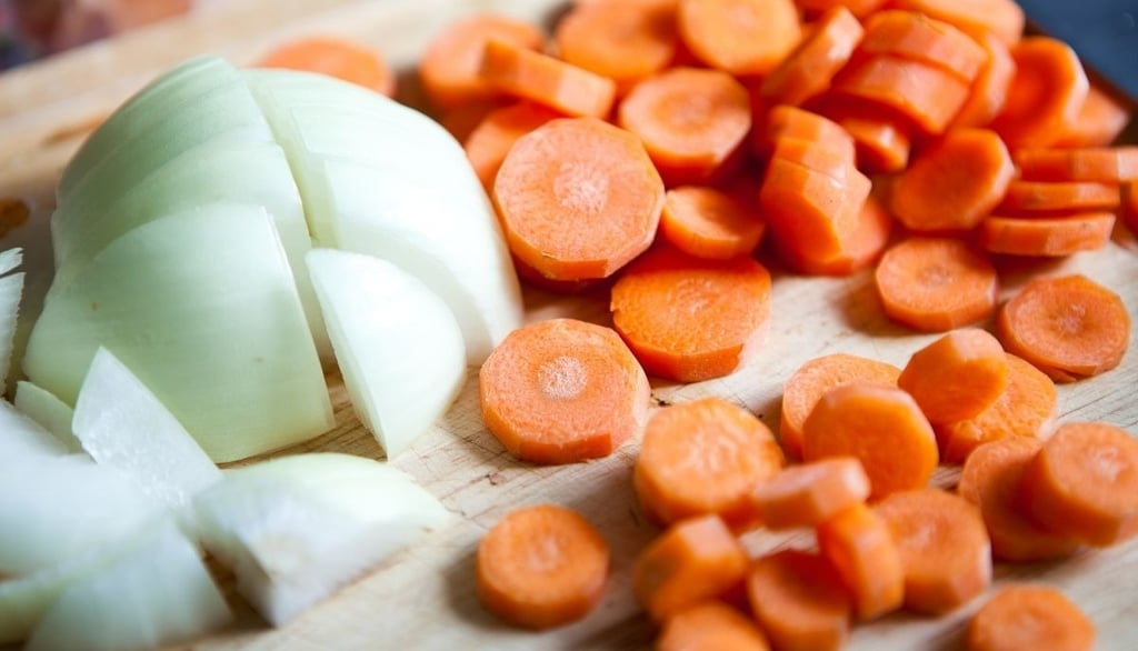 a cutting board with onions and carrots on it