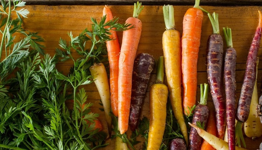 a bunch of colorful carrots are on a wooden table