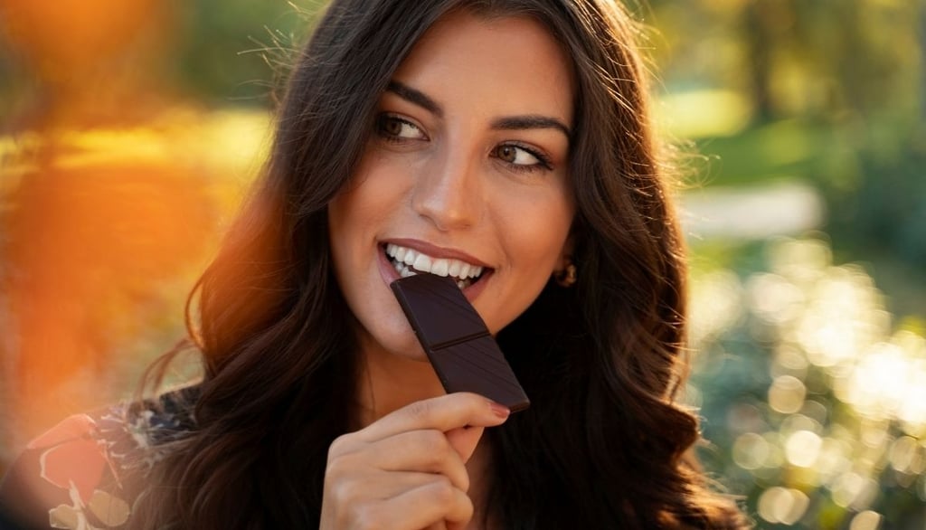 a beautiful woman eating vegan dark chocolate