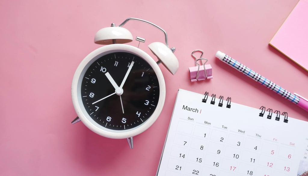 White alarm clock with pen and March calendar on a pink background