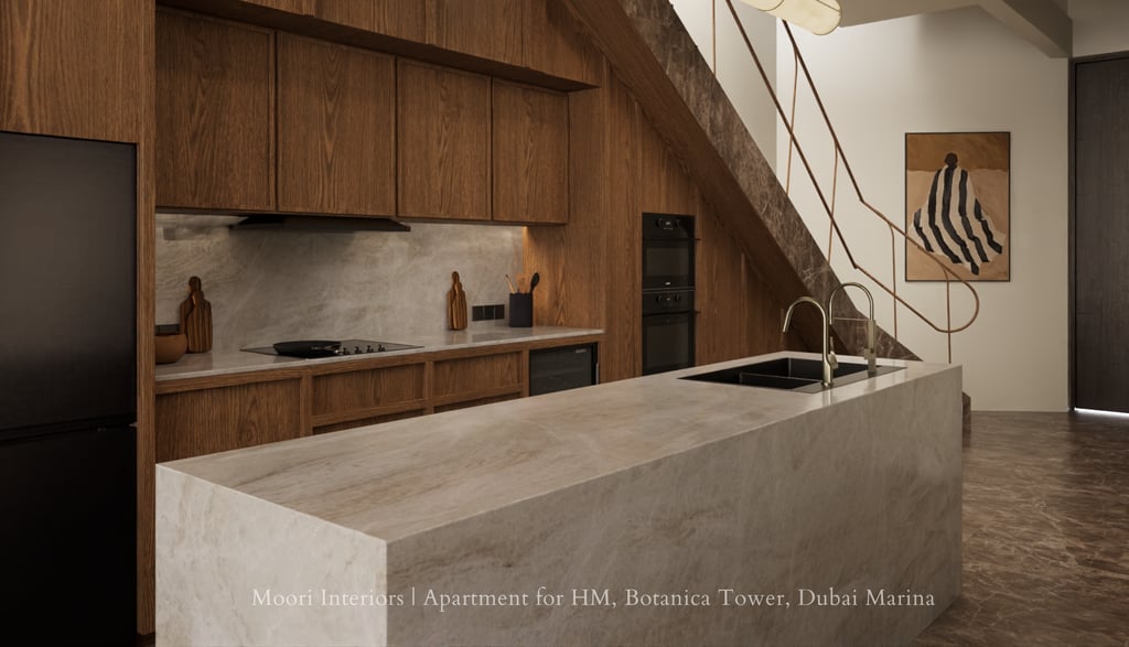 Warm wood kitchen with marble island under staircase, featuring integrated appliances and railing