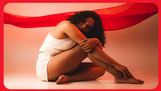 a woman sitting on the ground with a red scarf