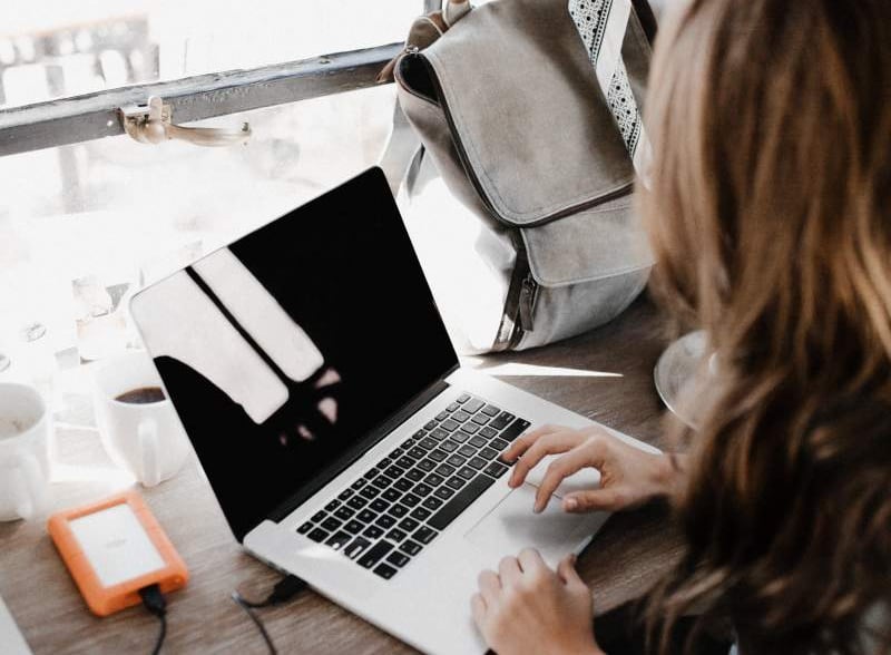 a woman sitting at a desk with a laptop and a backpack