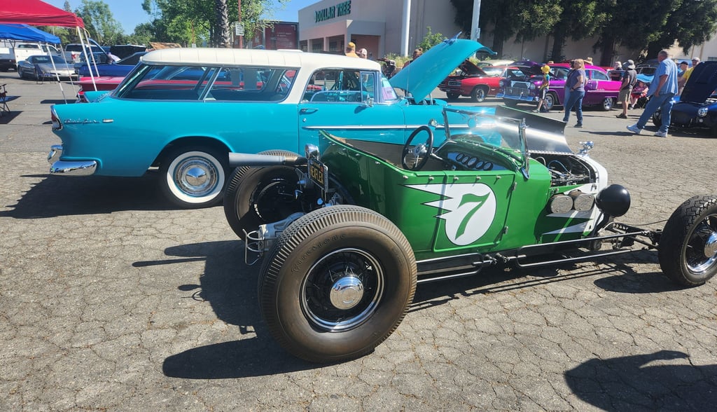 a green car with a number of cars parked in front of it