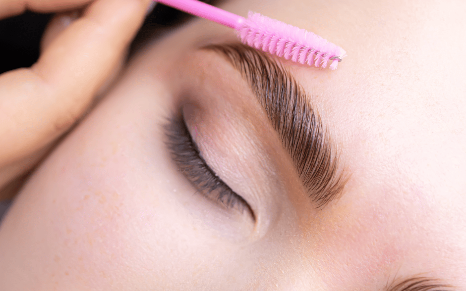 a woman brushing her brows after eyebrow lamination
