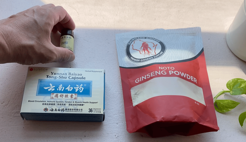 a person holding a bottle of notogingseng powder, with two other brands of same on windowsill
