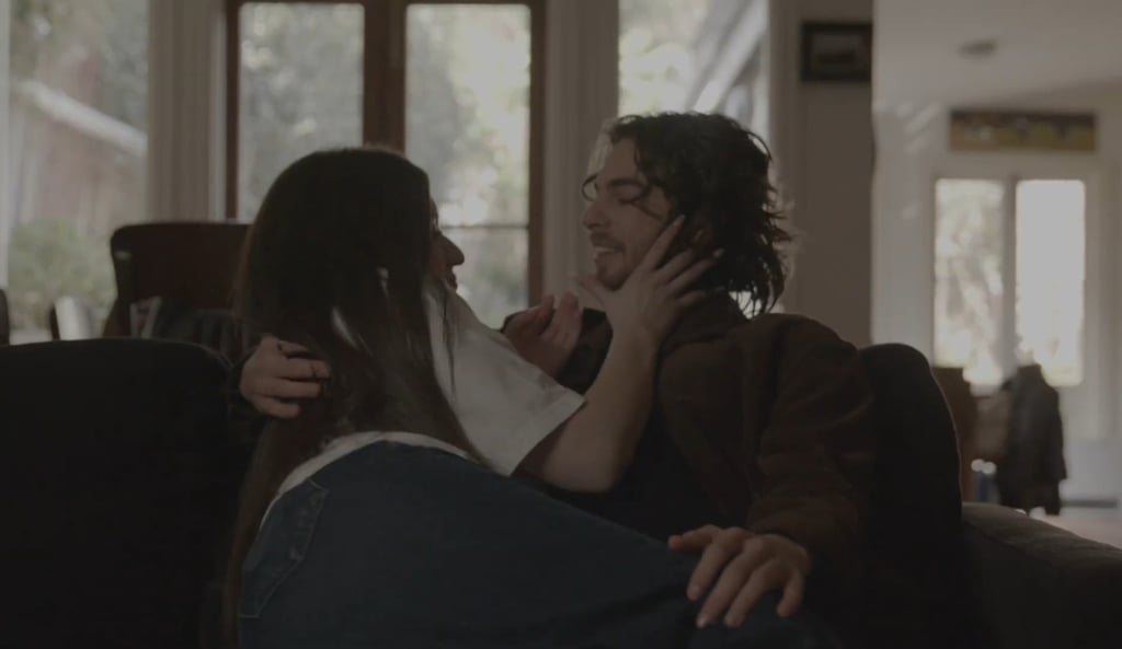 A young couple embracing each other and smiling, while relaxing on a sofa in a living room.