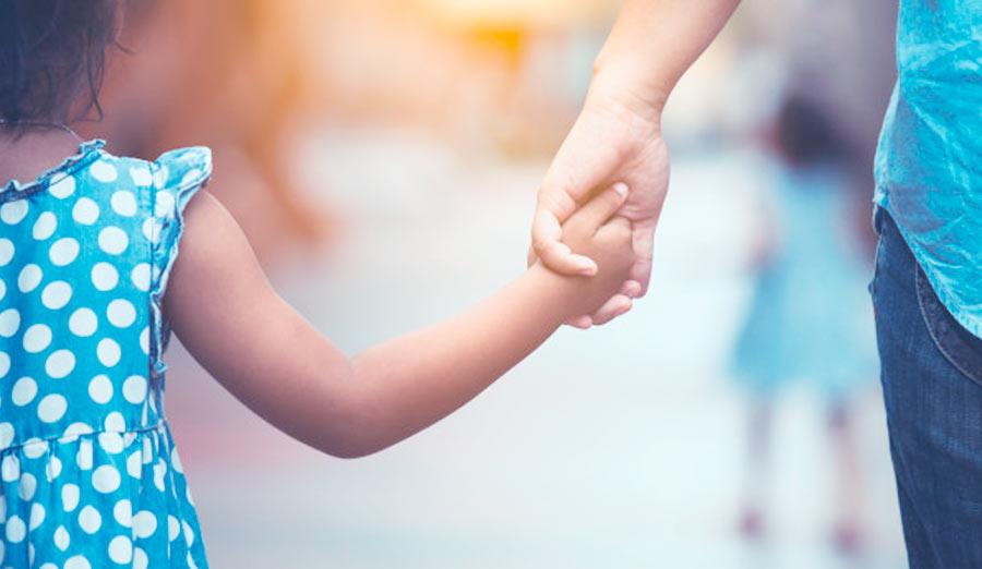 a young girl holding hands with her father