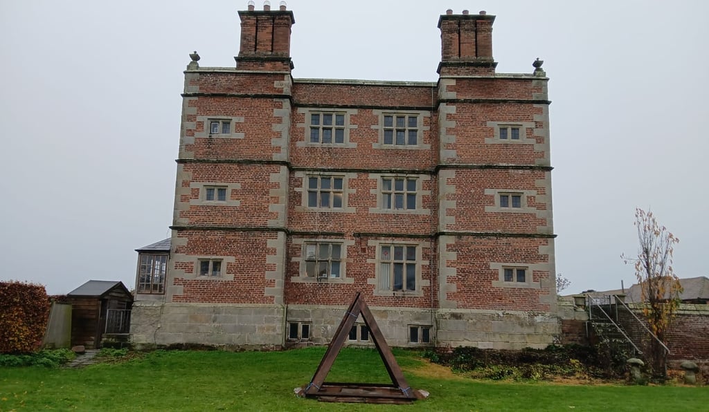 Soulton Hall in Shropshire with a pyramidal sculpture in front of it