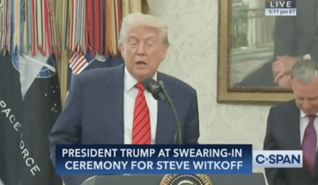 a man in a suit and tie is speaking into a microphone