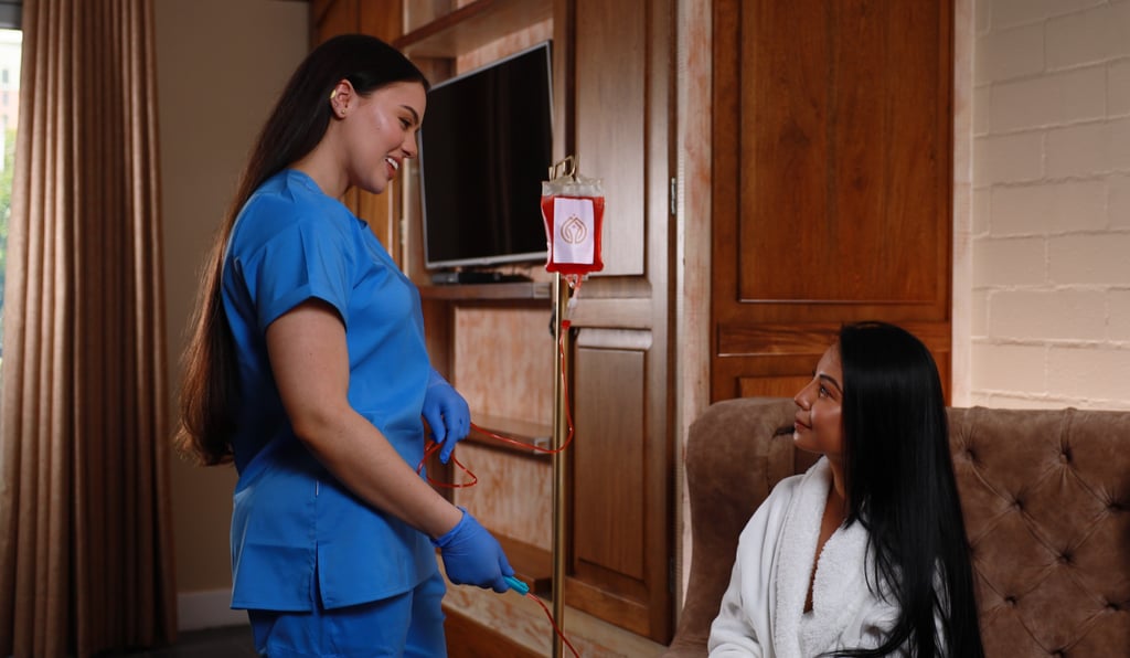 a nurse in scrubs providing IV therapy drip in a hotel