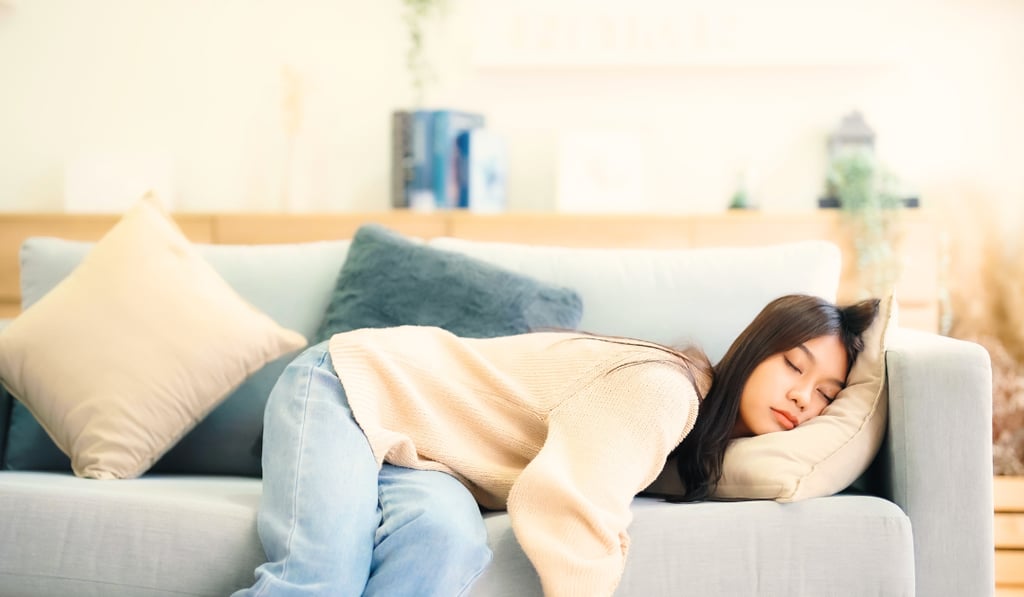 Woman resting on a sofa looking emotionally exhausted, representing stress, overwhelm, fatigue.