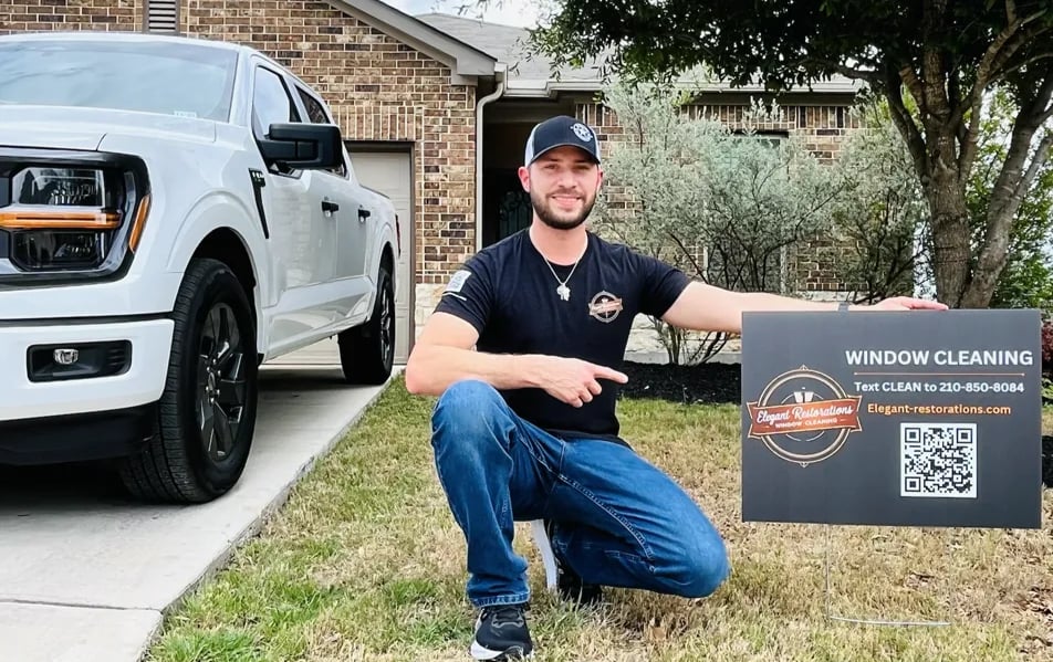 Alex Flores owner of Elegant Restorations Window Cleaning with yard sign in San Antonio TX
