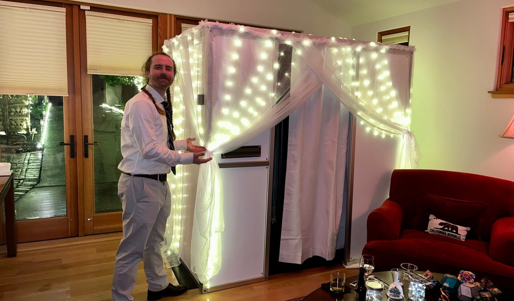 Mace from Bhoto Booth standing next to enclosed photo booth with fairy light draping at a Bay Area w