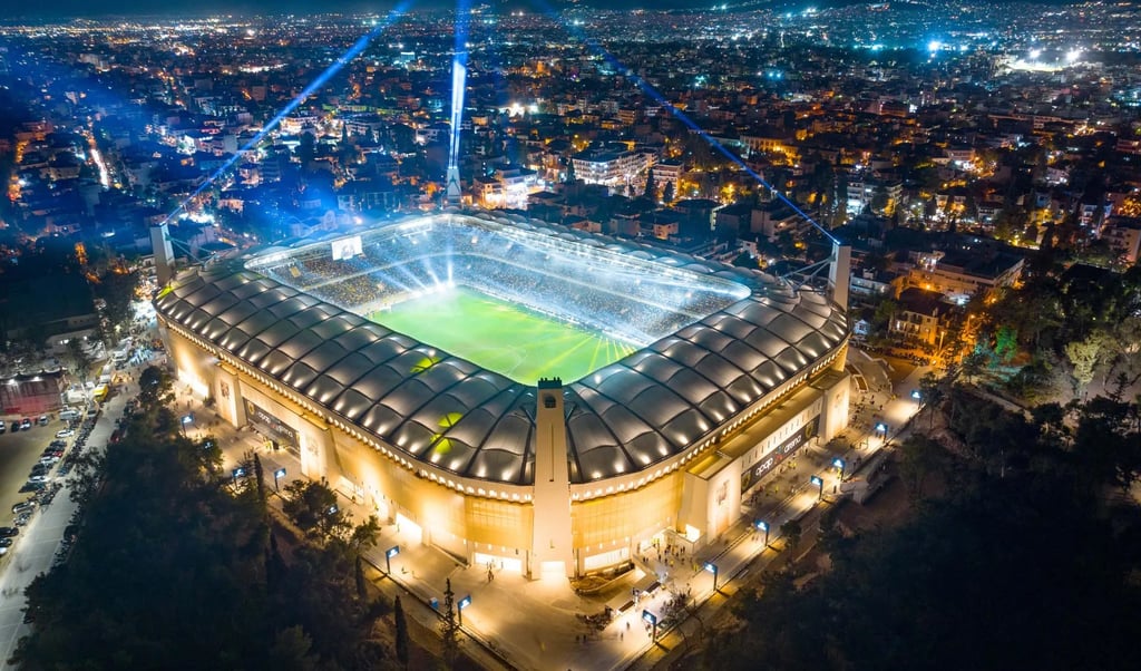 Luftaufnahme der OPAP Arena in Athen, Heimstadion von AEK Athen, mit vollem Spielfeld, Tribünen und umgebender Stadtkulisse