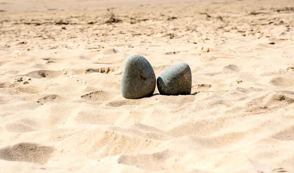 Deux galets sur le sable, symbole de l'espace de parole et la rencontre en thérapie pour adolescents