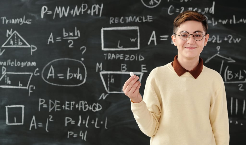 a boy in a white sweater and glasses standing in front of a blackboard