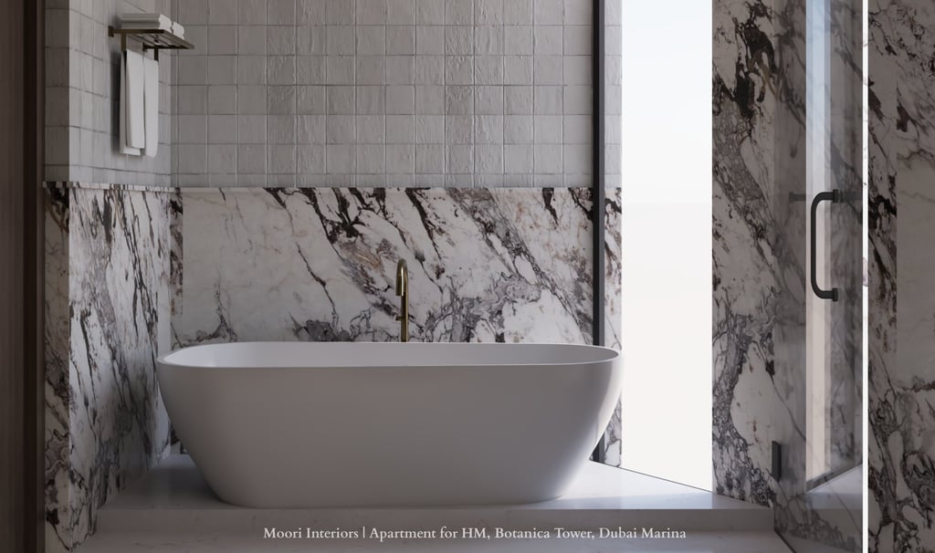 White tub in a bathroom with textured and Arabescato marble walls and a glass shower door.