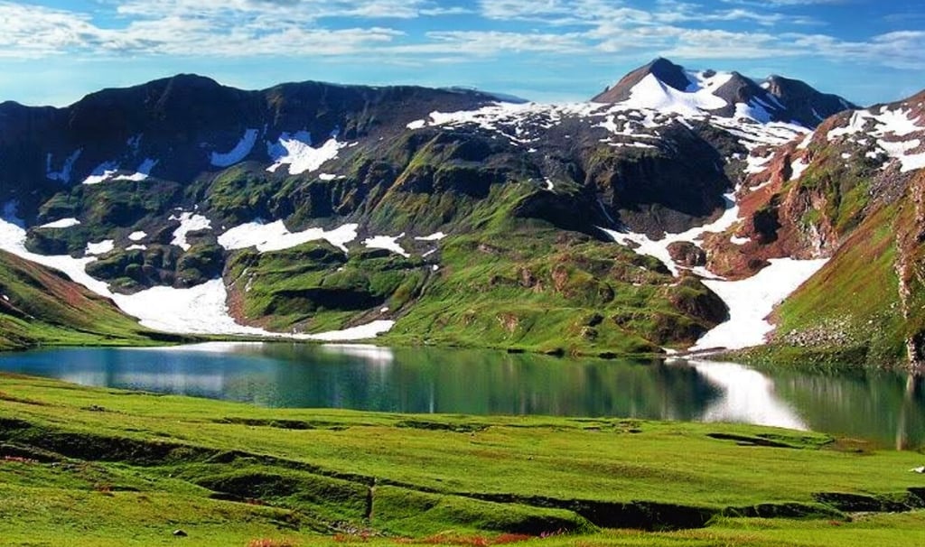 a mountain scene with Ansoo lake and mountains in the background
