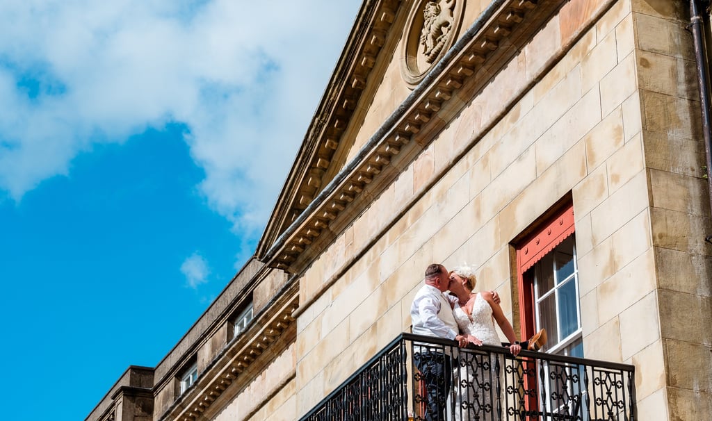 a bride and groom kissing on a balcony balcony