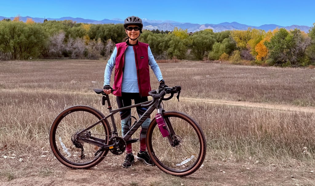 The author posing with her Canyon gravel bike against a distant mountain range backdrop