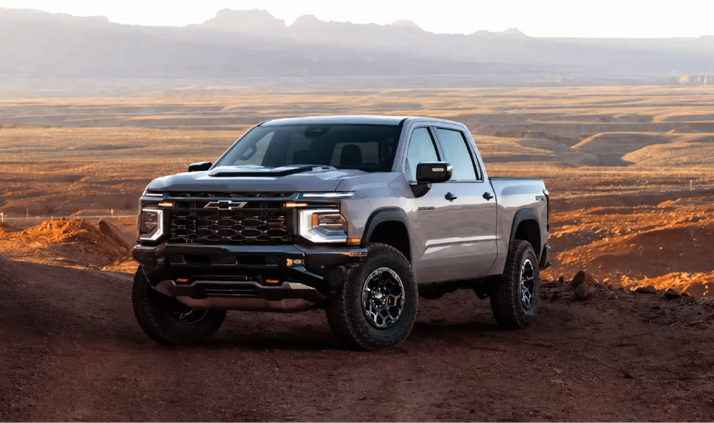 Chevrolet Silverado ZR2 prata em trilha off-road com paisagem desértica ao fundo.