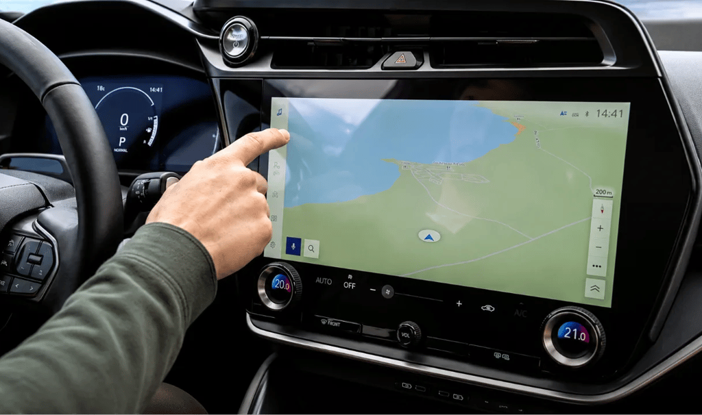 Motorista usando tela digital no painel de um carro moderno durante a condução