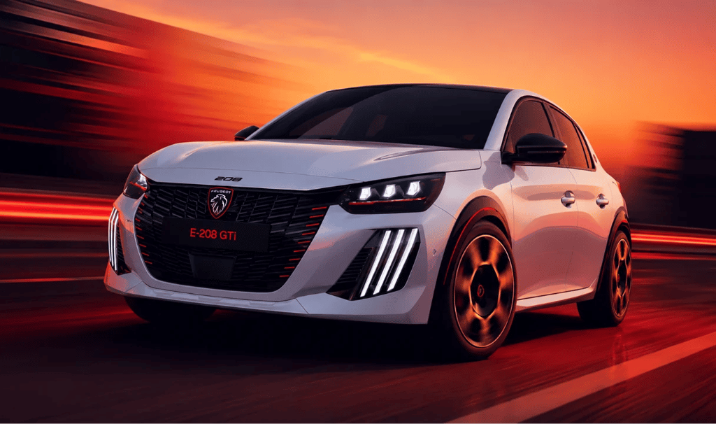 Peugeot E-208 GTi branco acelera em pista com visual esportivo e iluminação ao entardecer