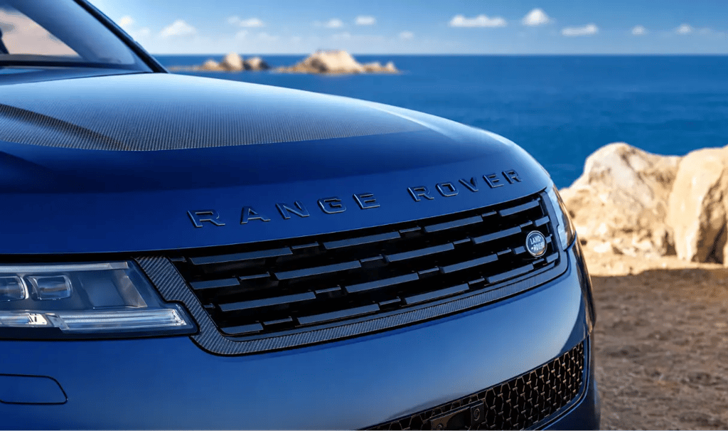 Range Rover azul em destaque com cenário costeiro ao fundo