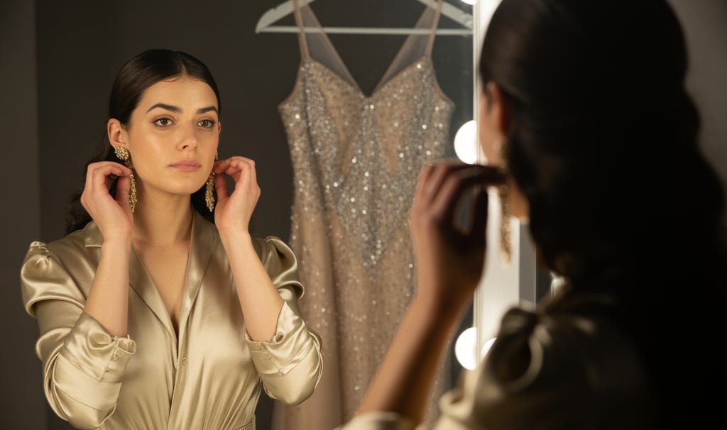 a woman in a gold dress is looking at her reflection in the mirror