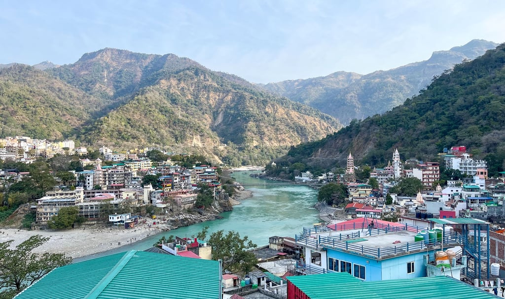 Scenic rooftop view overlooking the mountains and the cityscape of Rishikesh, India, under a clear sky.