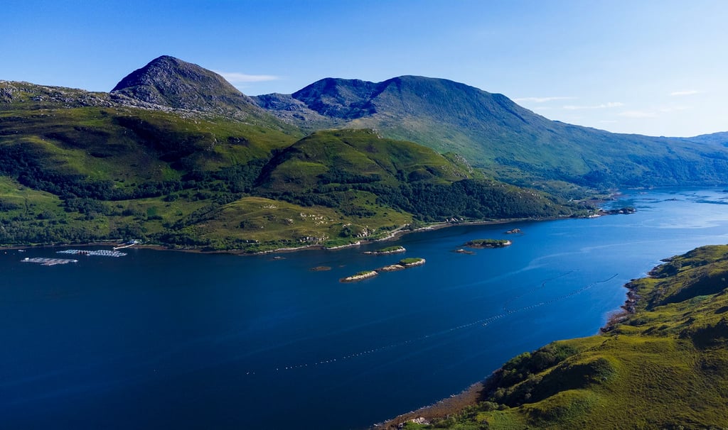 Aerial view of a scenic blue sea loch surrounded by green mountains in the Scottish Highlands.
