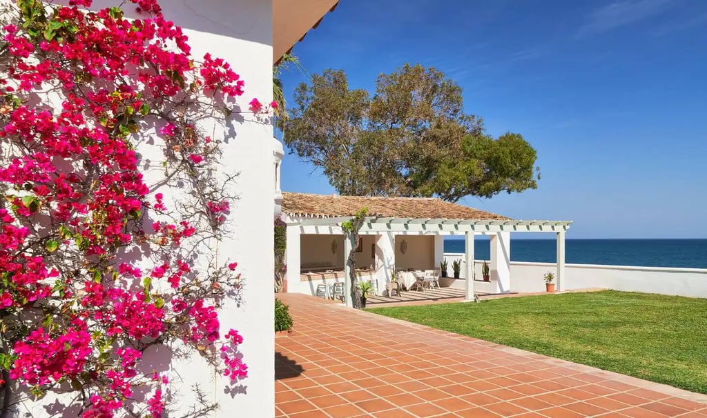 Luxury Marbella villa with blooming pink bougainvillea, terracotta patio, and ocean views.