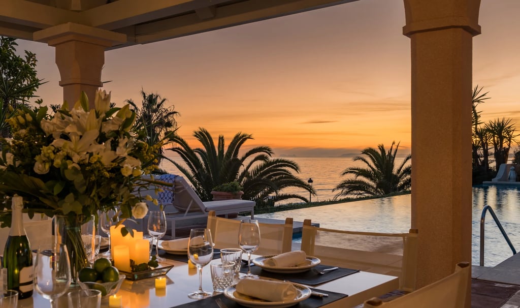 Candlelit dining setting at sunset beside infinity pool and ocean