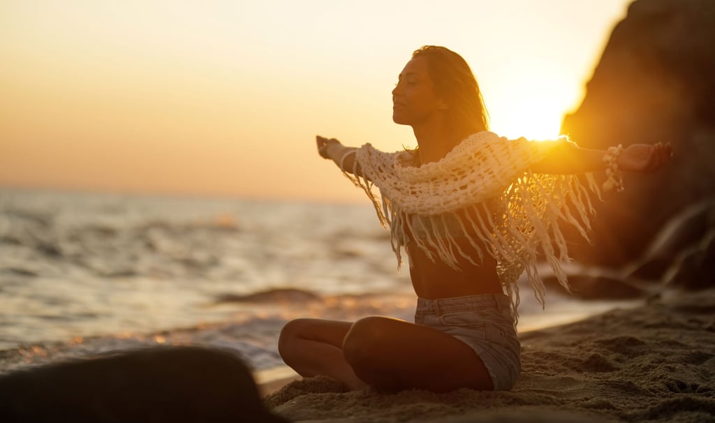 a woman sitting on a beach with her arms outstretched out