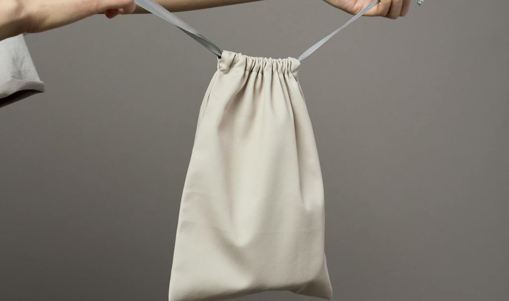 a person holding up a plain white draw-string bag