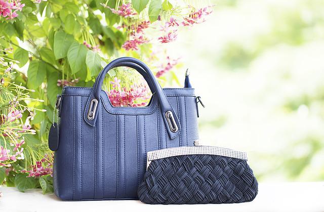 Navy blue handbag and matching clutch displayed outdoors.
