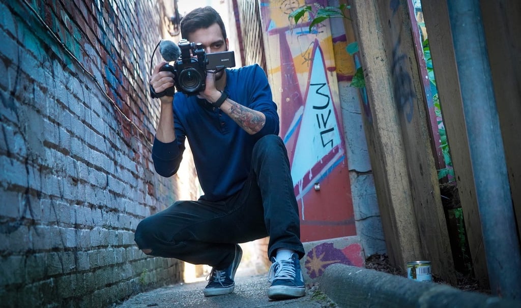 Corbin Veltum, holding a video camera in an alleyway