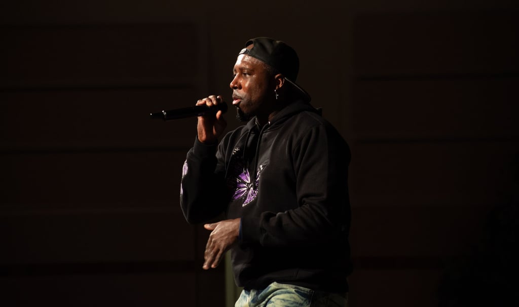 A rapper wearing a backwards baseball cap, standing on a stage at church