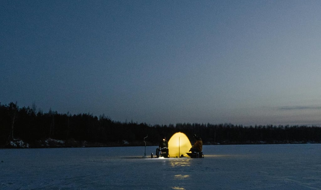 Ice fishing tent glowing on frozen lake at dusk, cold weather survival and winter sheltering